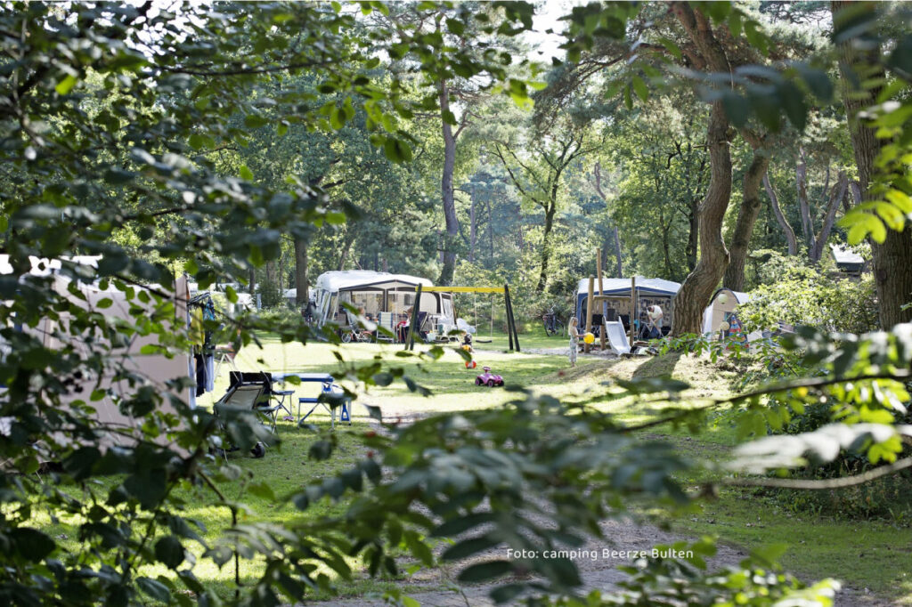 meerdere caravans op camping Beerze Bulten. Kinderen spelen op de voorgrond in de speeltuin